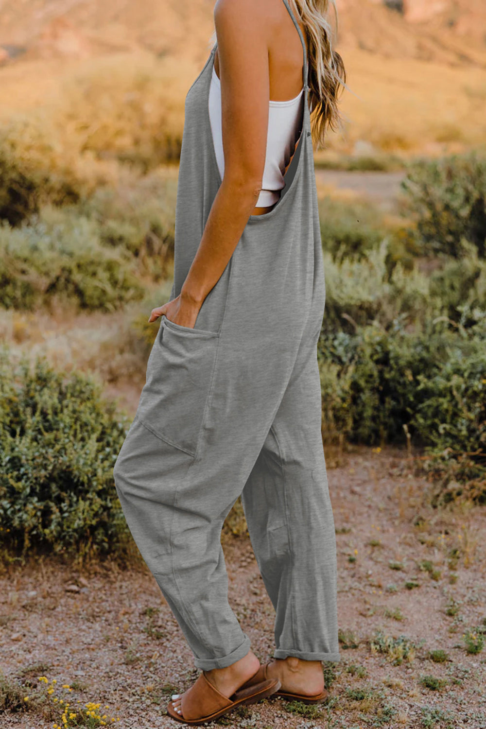 Gray sleeveless jumpsuit with wide legs and pockets.