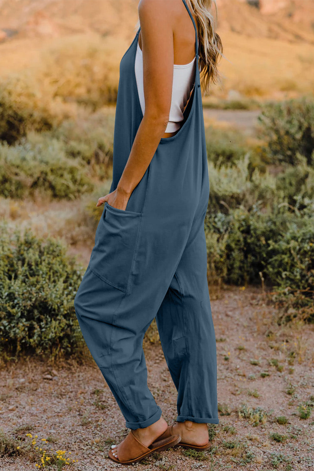 Loose-fitting blue jumpsuit with spaghetti straps and pockets.