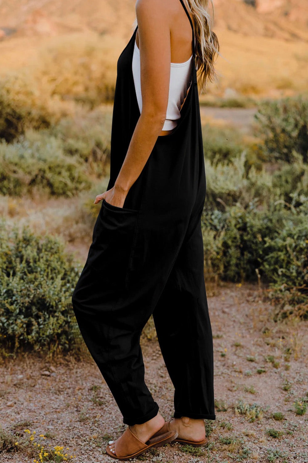 Black sleeveless jumpsuit with wide legs worn by a person in a desert setting.