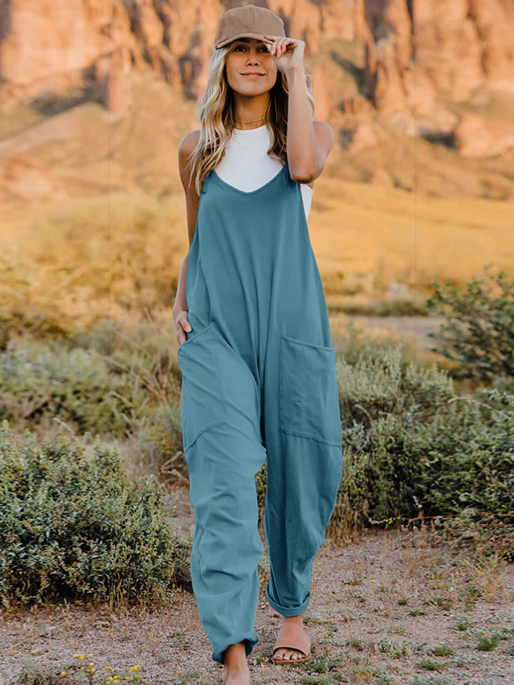 Teal-colored loose-fitting jumpsuit or overalls worn over a white top.