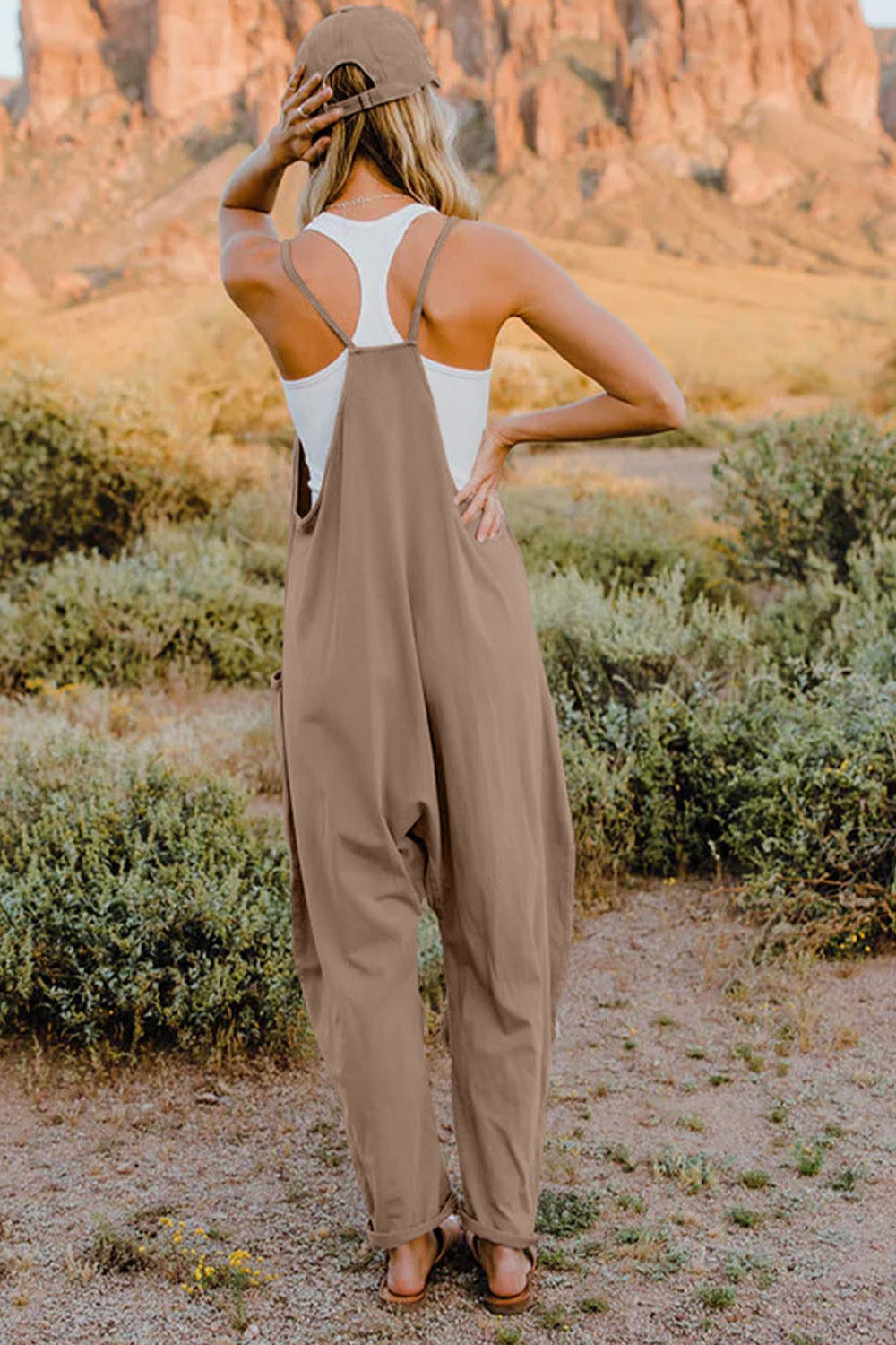 Tan overalls with a white tank top underneath, worn by a person standing outdoors.