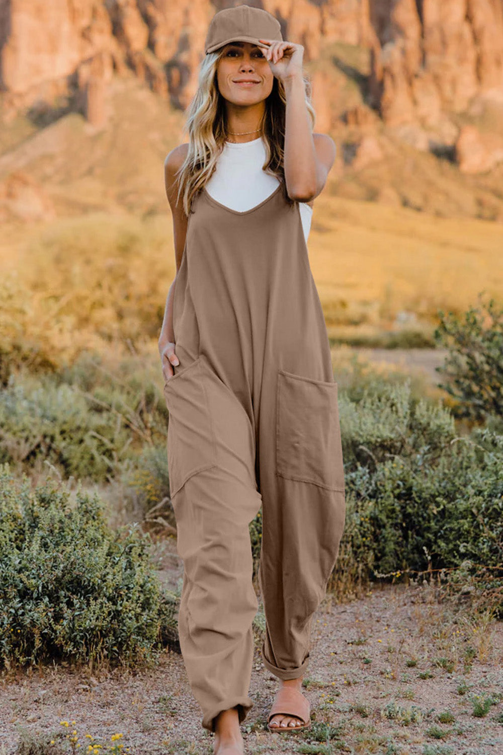 Woman wearing a loose-fitting tan jumpsuit and a baseball cap.