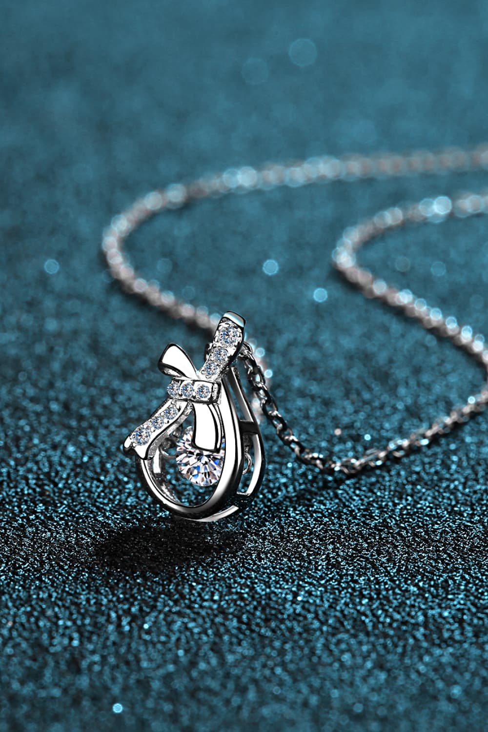 Elegant silver pendant necklace featuring a round diamond encircled by bow-like design - silver / one size